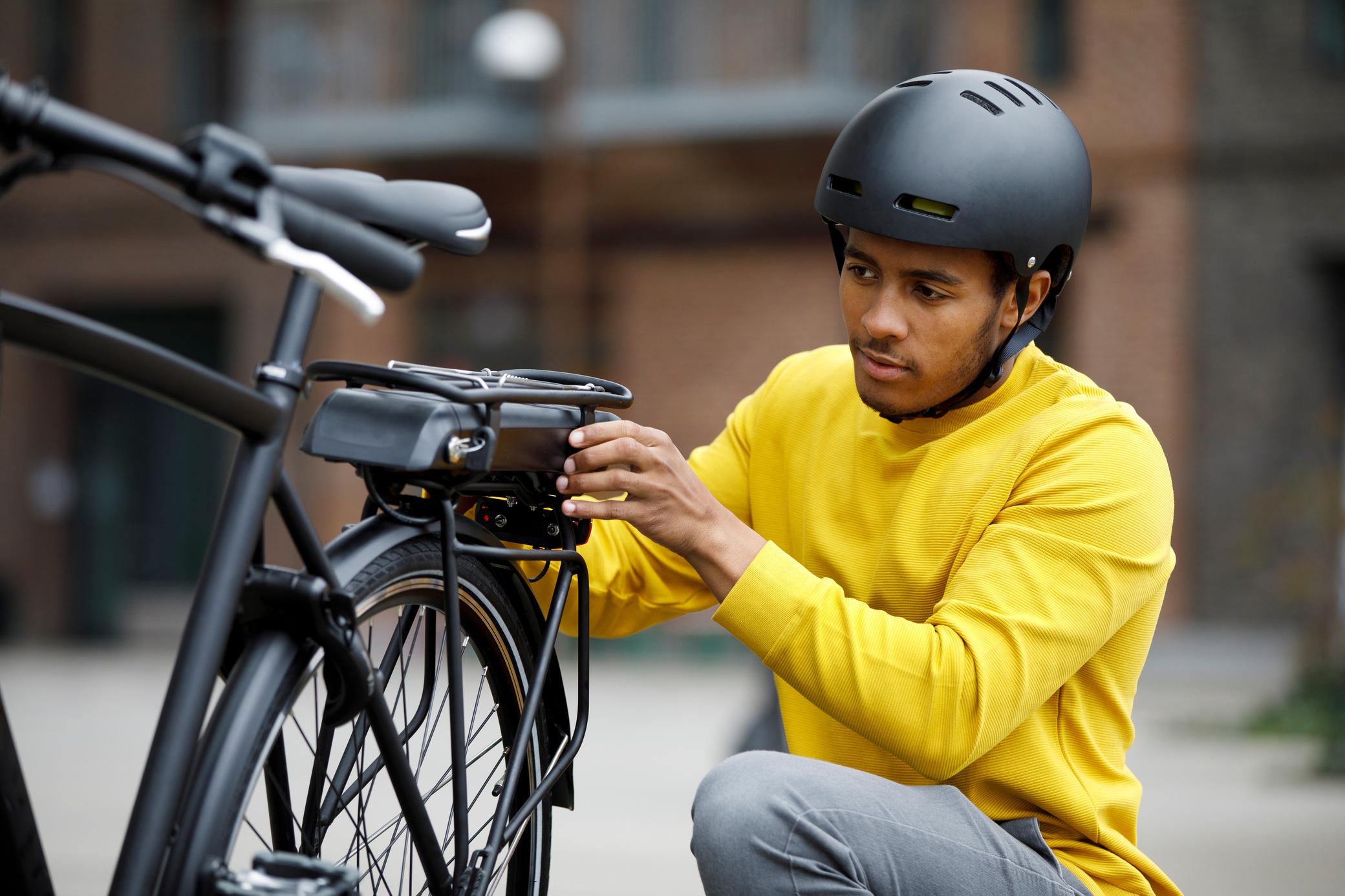 Mann mit gelbem Pulli untersucht sein E-Bike Fahrrad