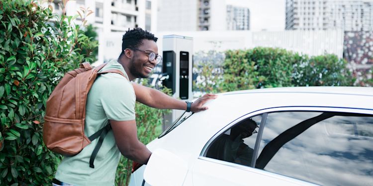 E-Auto ohne eigene Wallbox: Lohnt sich das? Ein Mann mit Rucksack lädt sein E-Auto an einer öffentlicher Ladesäule