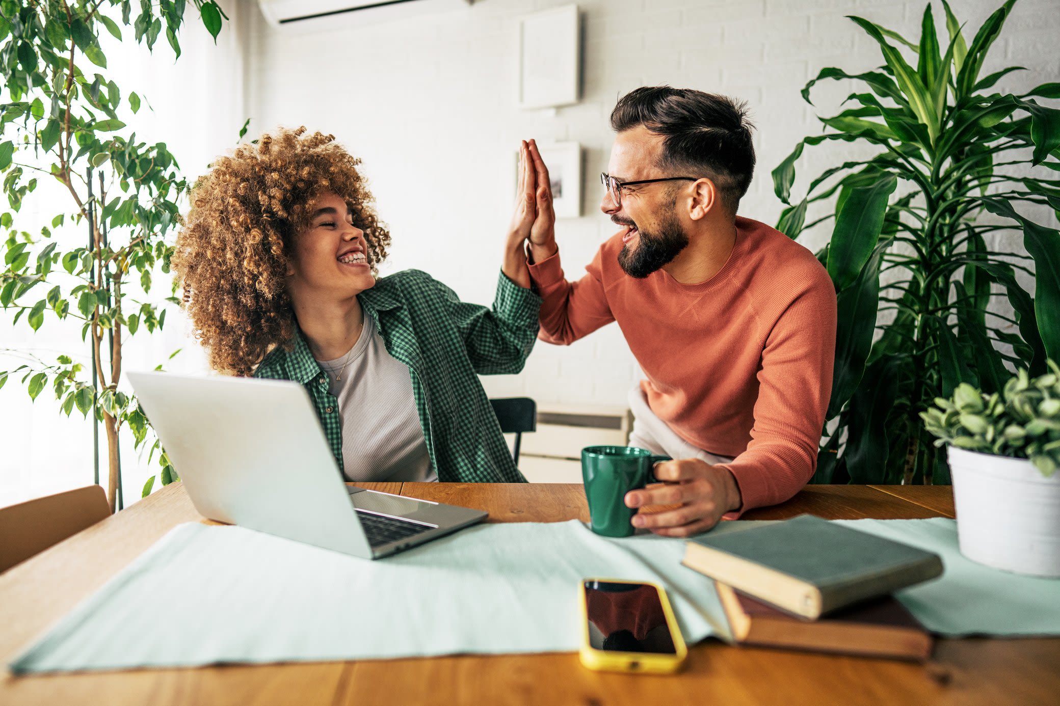 Energie und Kosten sparen - Es gibt viele Möglichkeiten Mann und Frau mit Laptop bei der Arbeit geben sich ein High Five