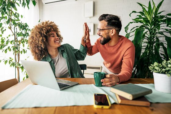 Energie und Kosten sparen - Es gibt viele Möglichkeiten Mann und Frau mit Laptop bei der Arbeit geben sich ein High Five