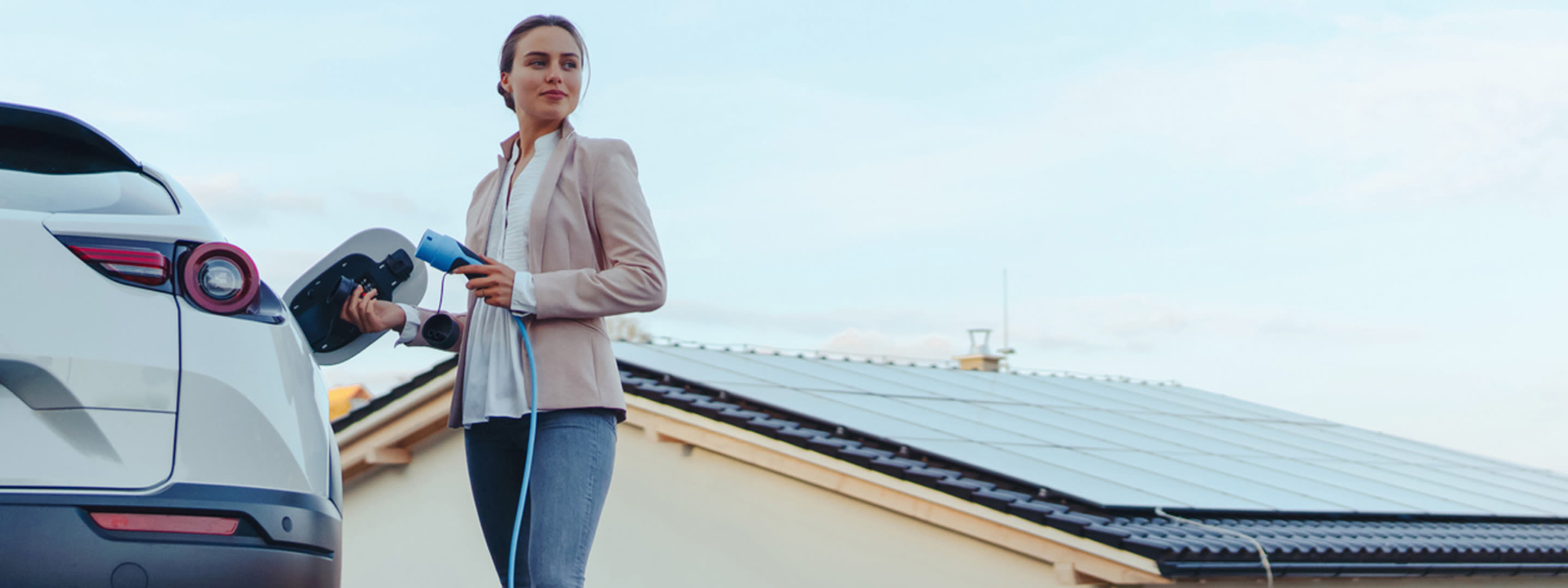 Wallbox, Wärmepumpe, Kühlanlage und Speicher flexibel ins Netz einbinden Frau lädt ihr E-Auto - mit eigener Solaranlage auf dem Dach