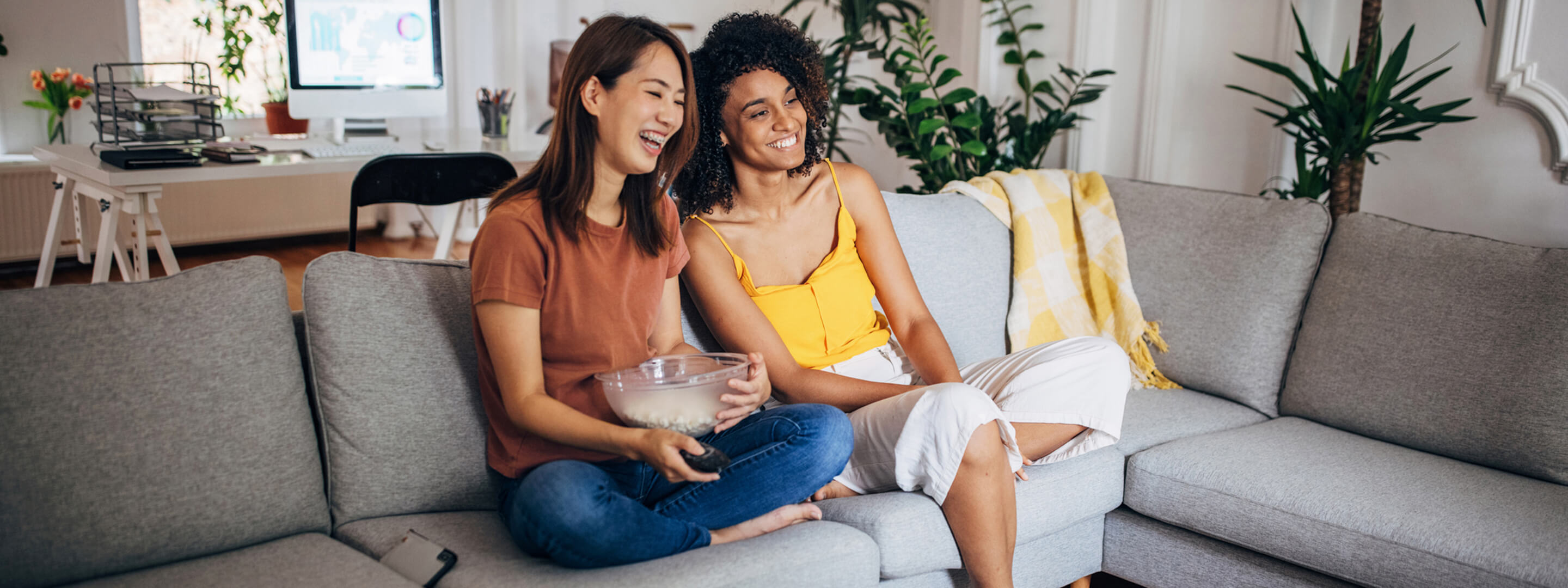 Zwei Frauen sitzen mit Popcorn vor dem Fernseher