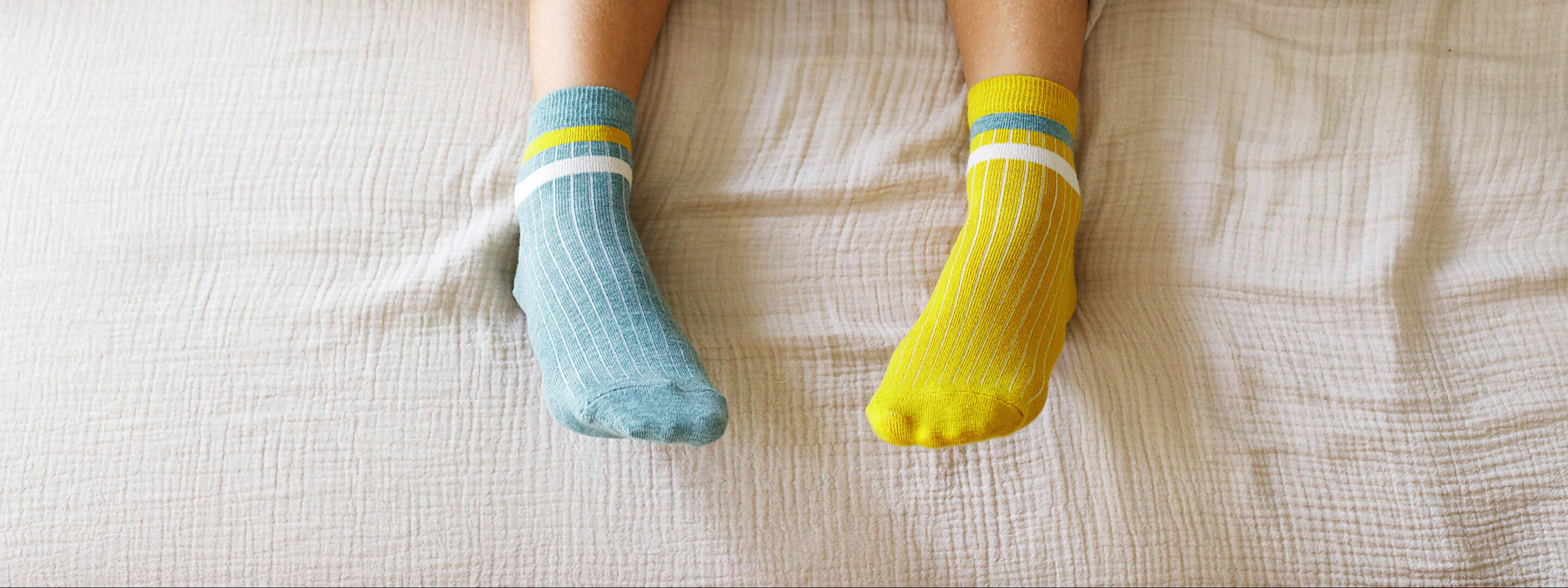 Füße in warmen Stricksocken liegen auf einer Bettdecke