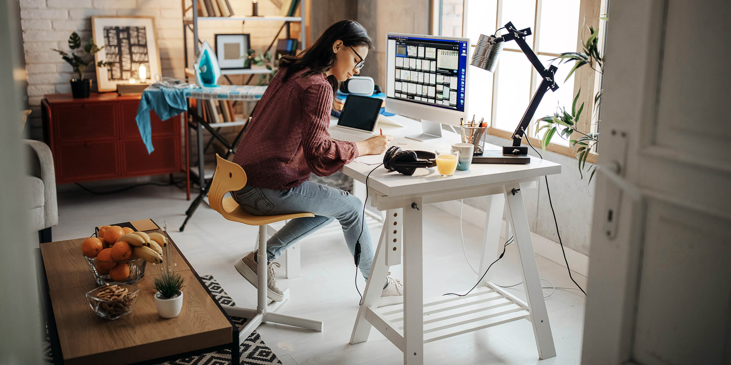 Eine Frau sitzt an ihrem Schreibtisch und arbeitet im Home Office.