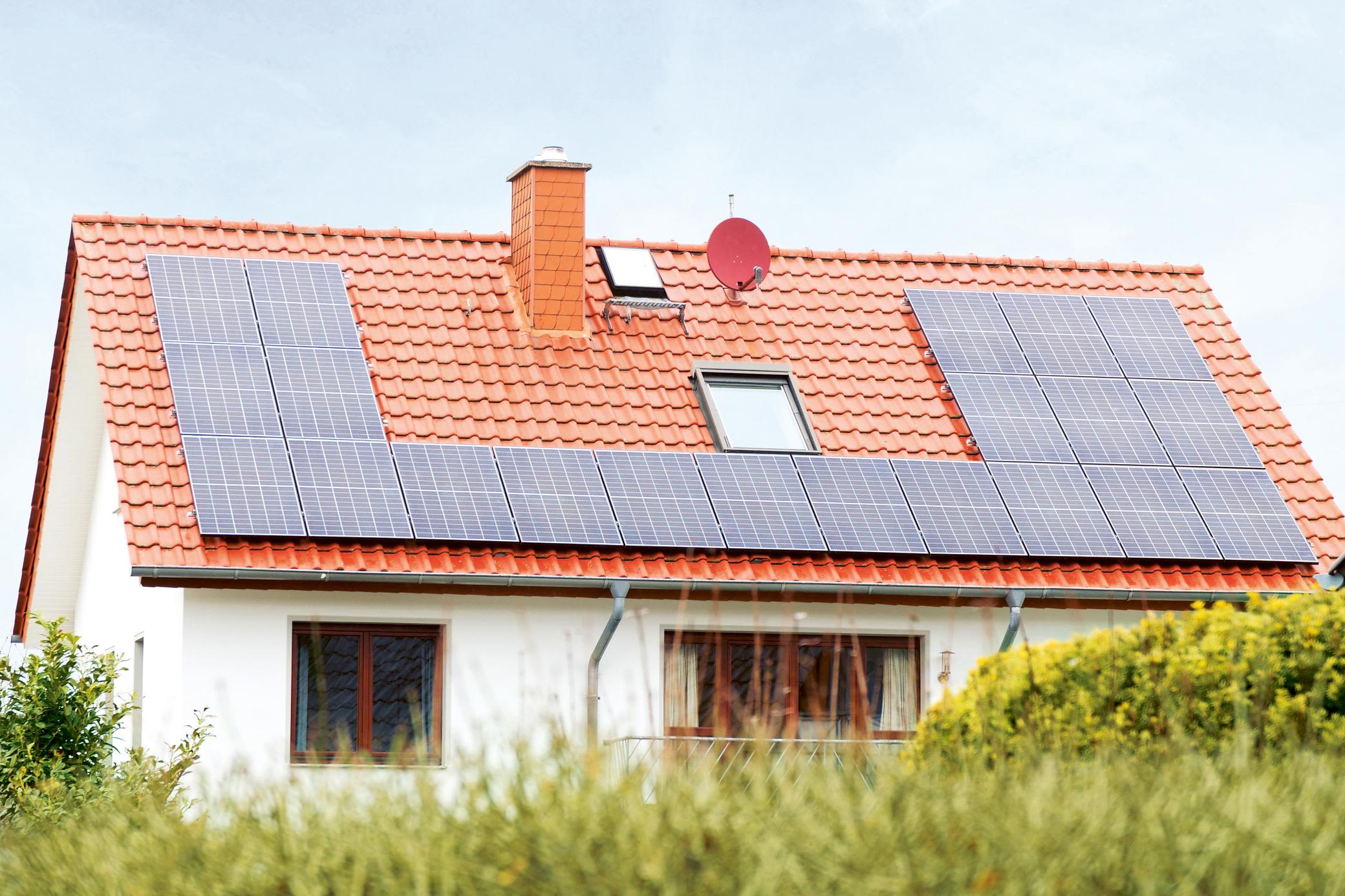 Größter Kostenpunkt: Anschaffung und Errichtung einer Solaranlage Haus mit einer Solaranlage auf dem Dach hinter einer Hecke