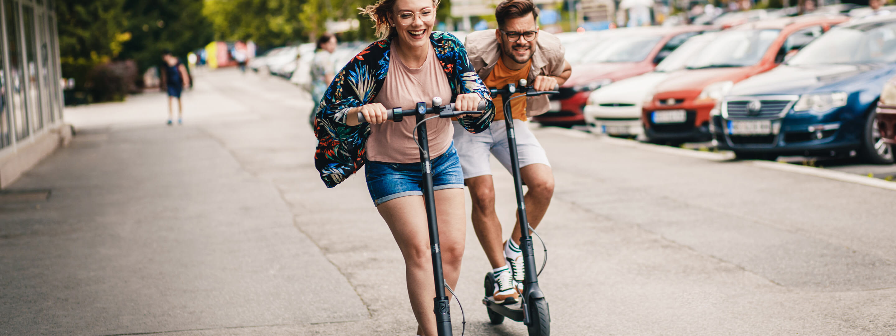 Spaß mit dem Elektroroller? Ja mit dem richtigen Tipps geht's los. Junges Paar hat Spaß und fährt mit E-Scooter durch die Stadt
