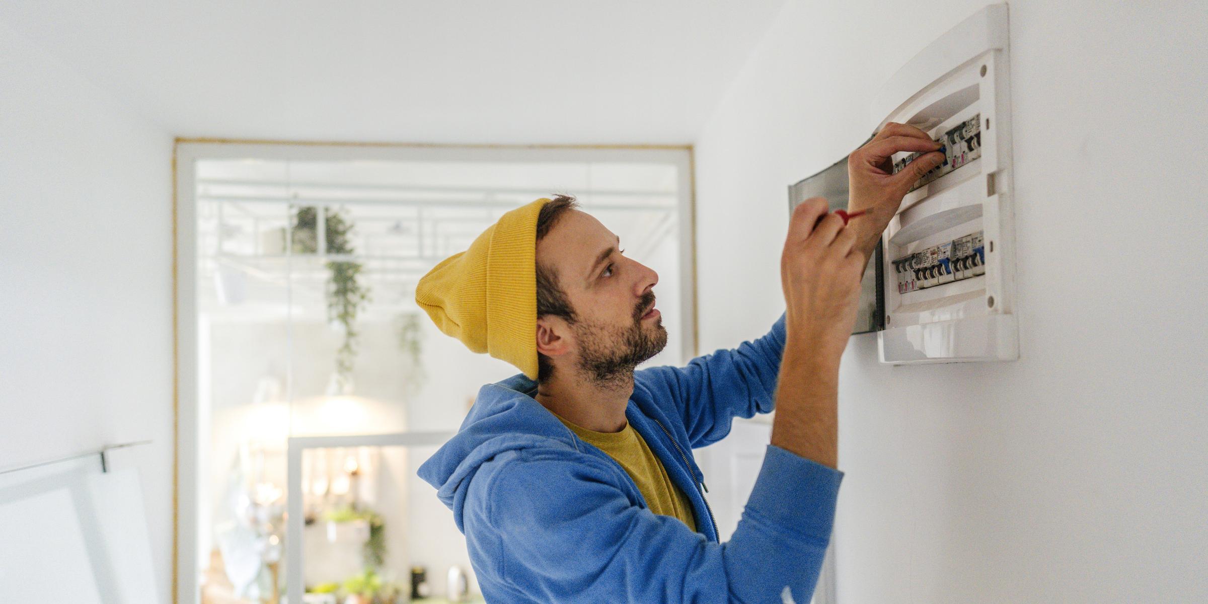 Junger Elektriker arbeitet an einen Sicherungskasten.