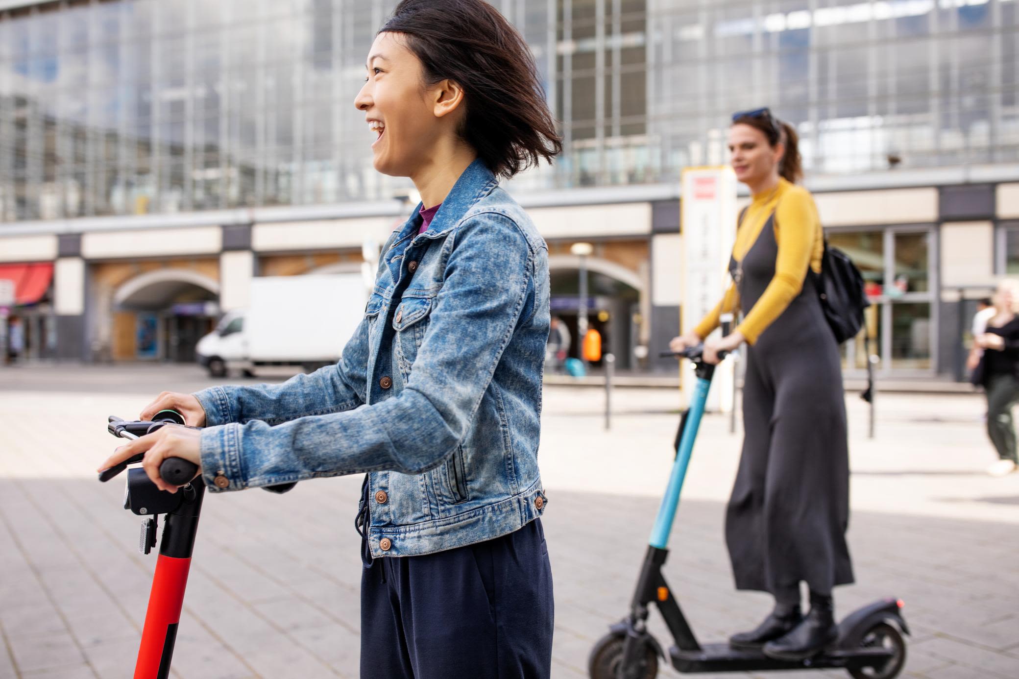 E-Scooter werden gern für die letzte Meile genutzt Zwei junge Frauen fahren mit dem E-Scooter in der Stadt