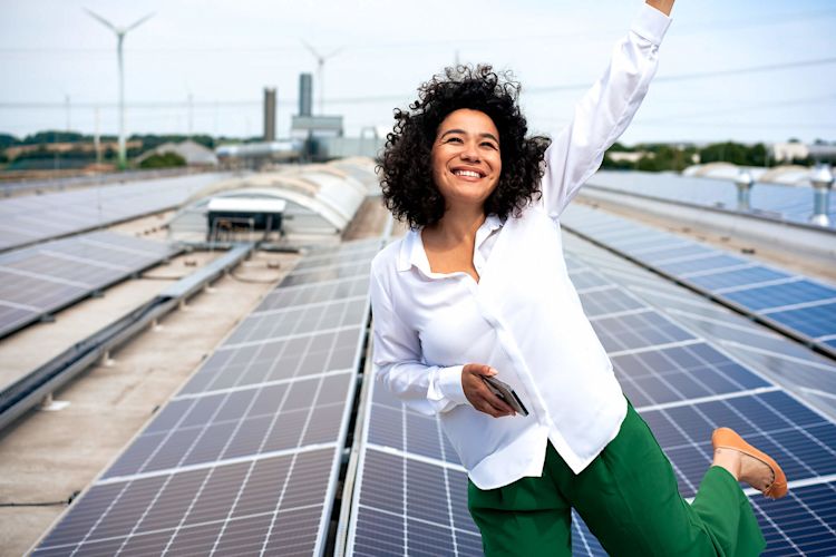 Happy mit Strom aus Photovoltaik Eine Frau steht freudestrahlend auf einem Solar Dach.