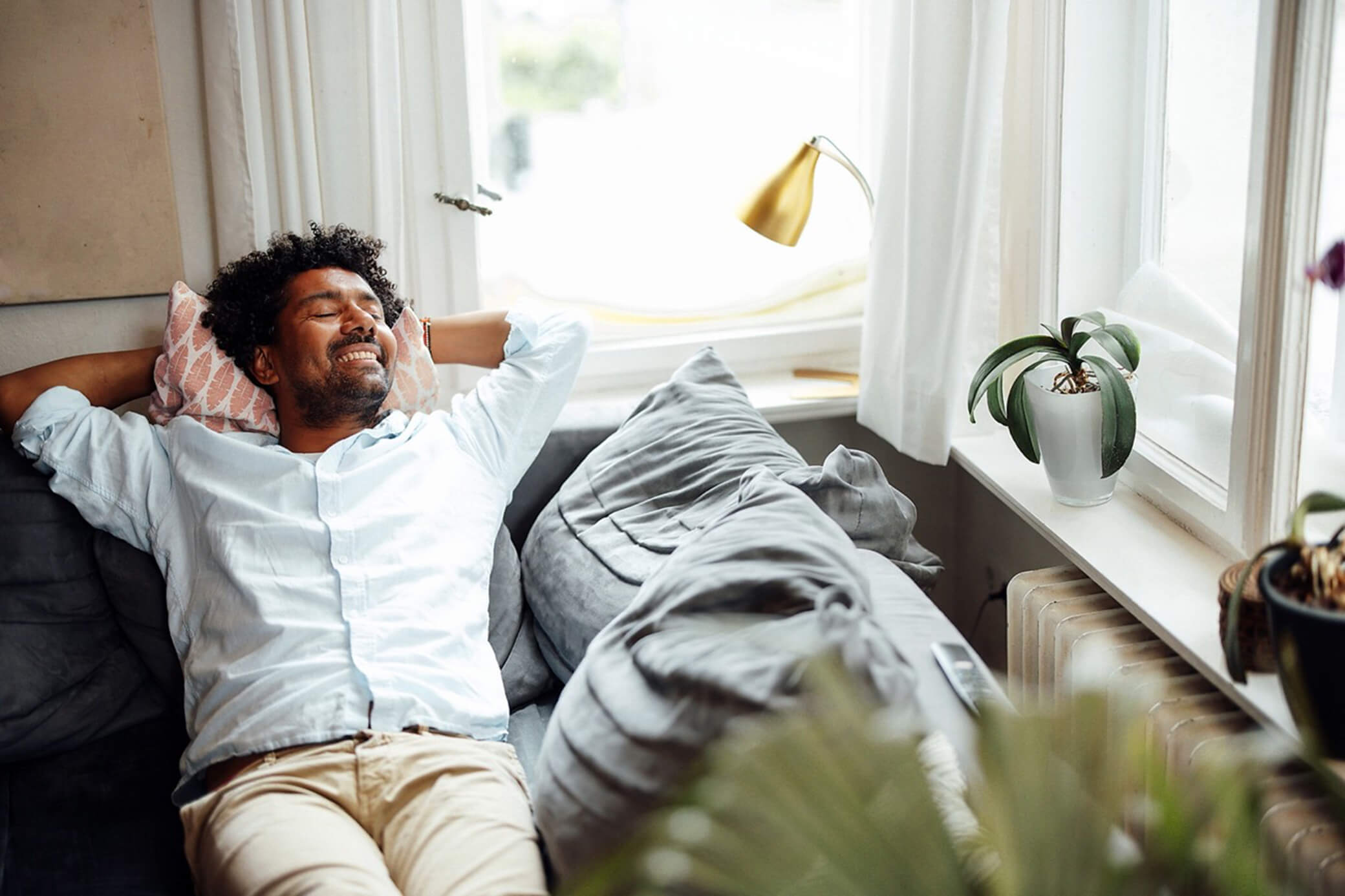 Entspannt dein zuhause genießen, dank smarter Energie Ein Mann entspannt sich zuhause auf der Couch