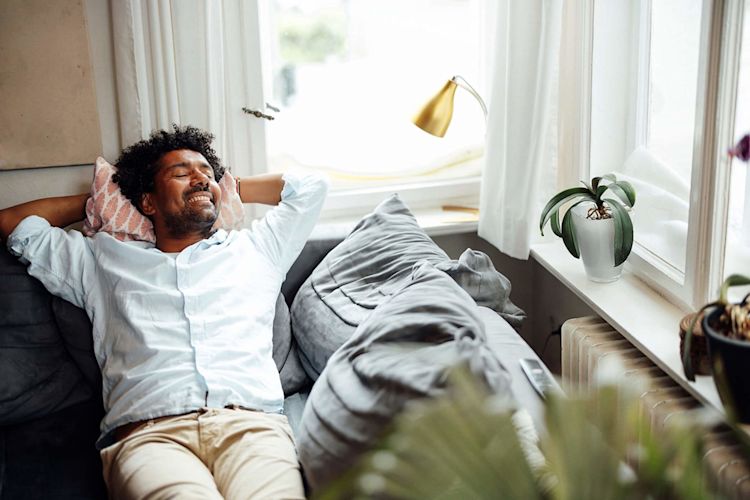 Entspannt dein zuhause genießen, dank smarter Energie Ein Mann entspannt sich zuhause auf der Couch
