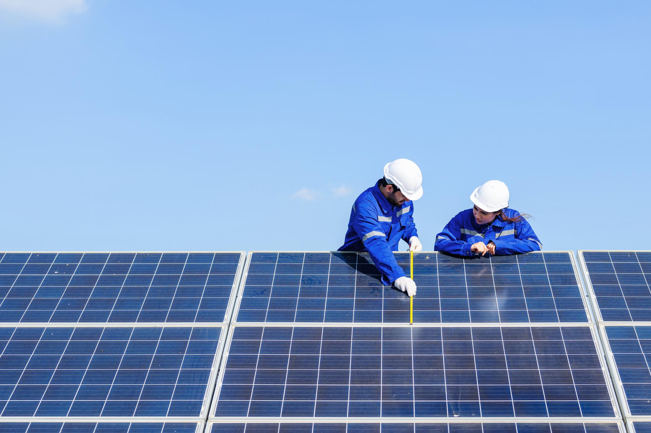 Solarmodule einer Anlage sind langlebig und wartungsarm Zwei Techniker überprüfen Solaranlage auf einem Dach