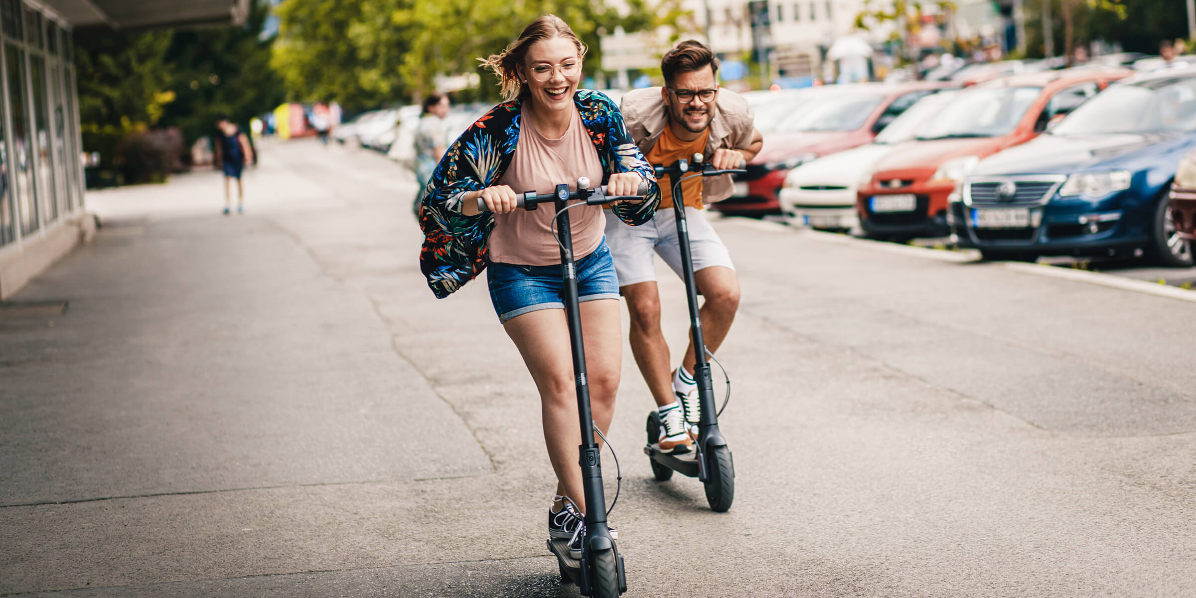 Junges Paar hat Spaß und fährt mit E-Scooter durch die Stadt.