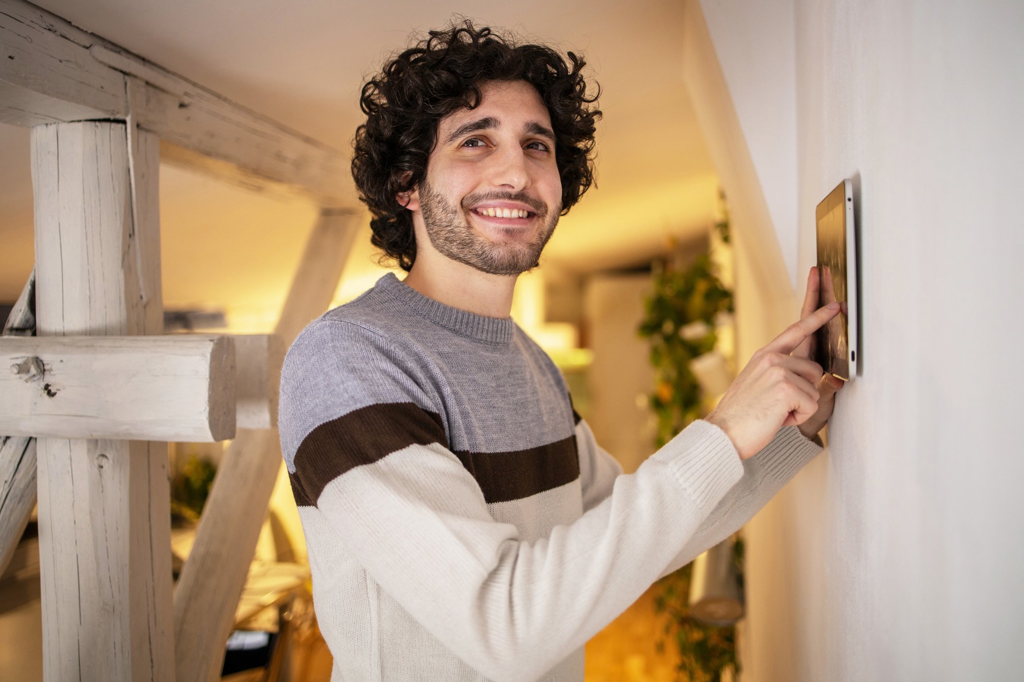 Mann steuert sein HEMS zuhause über ein Tablet an der Wand