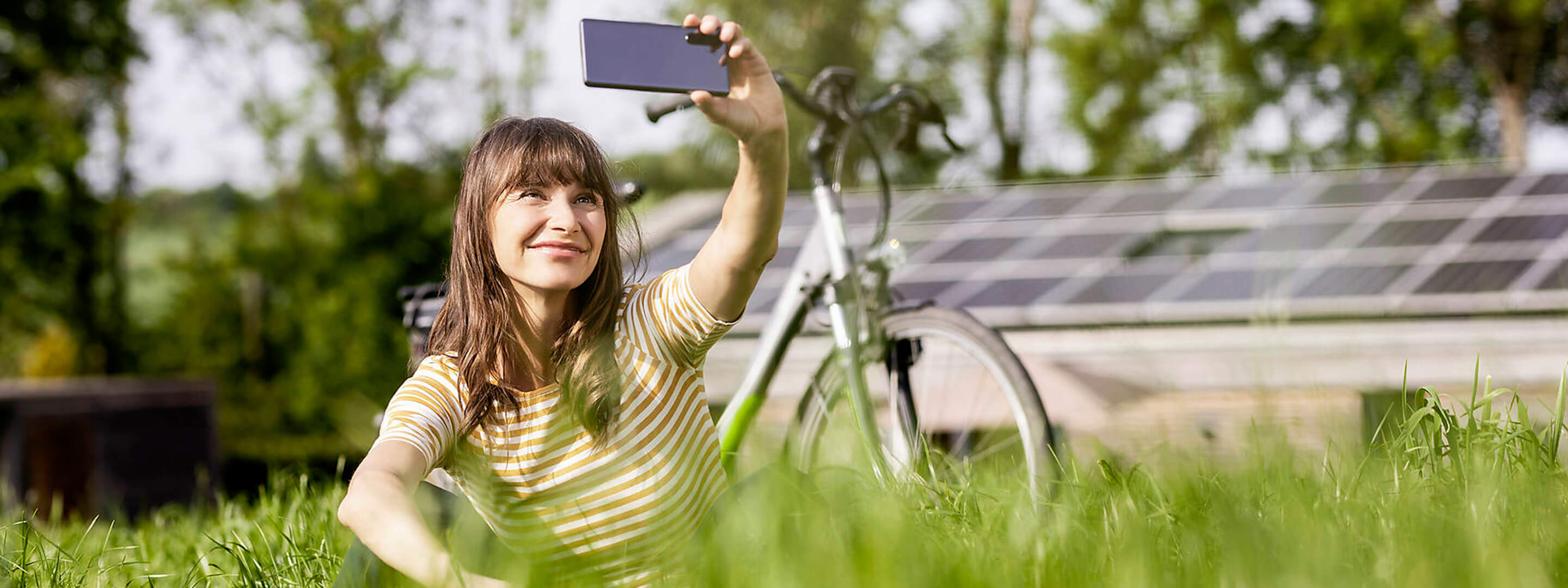 Photovoltaikanlage einfach gemacht – so holst du sie dir auf dein Dach Eine Frau mit Fahrrad macht ein Selfie vor ihrer Photovoltaikanlage.