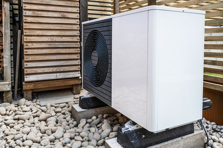 Eine Wärmepumpe nutzt vorwiegend Energie aus der Umwelt Einheit einer Luft-Wasser-Wärmepumpe vor dem Haus im Unterstand