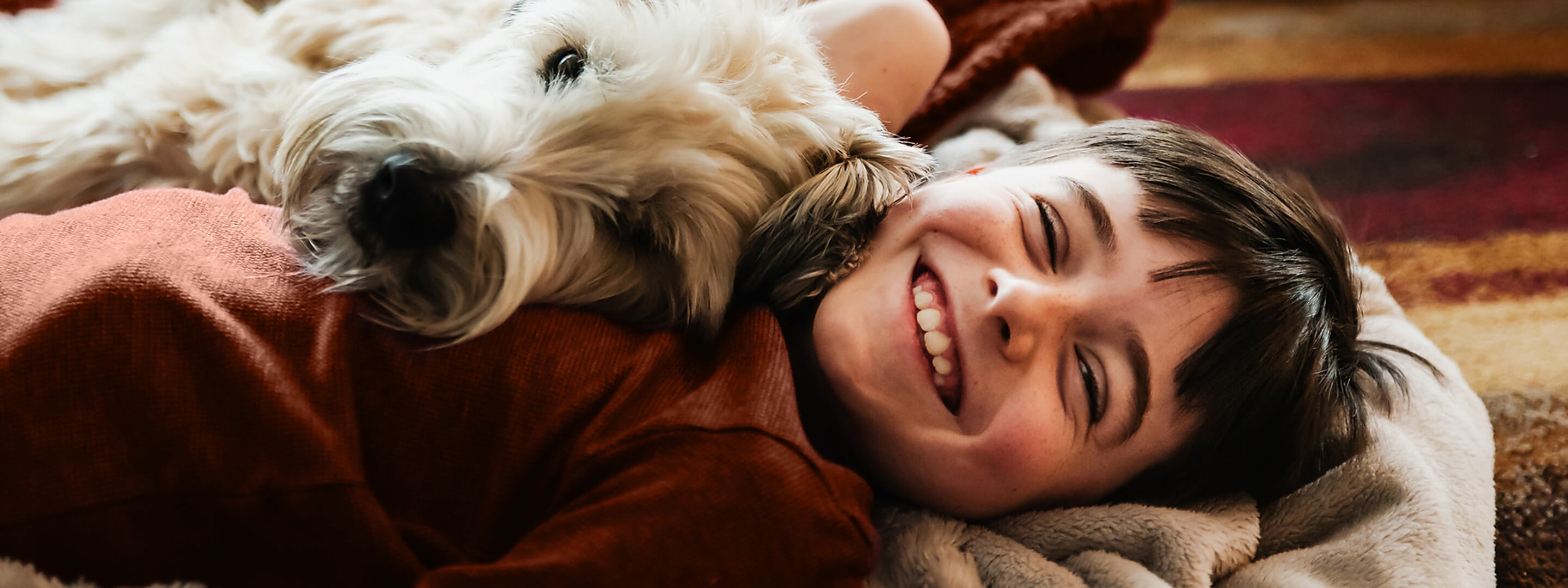 Ein Junge kuschelt mit einem Hund auf dem Boden
