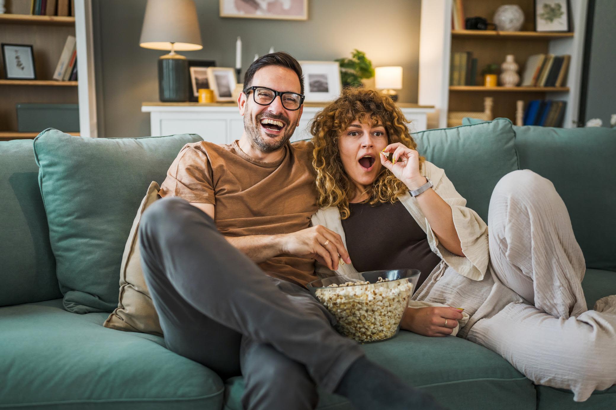 Fernsehen mit einem effizienten Gerät mehr genießen Junges Paar beim Fernsehen auf dem Sofa mit Popcorn