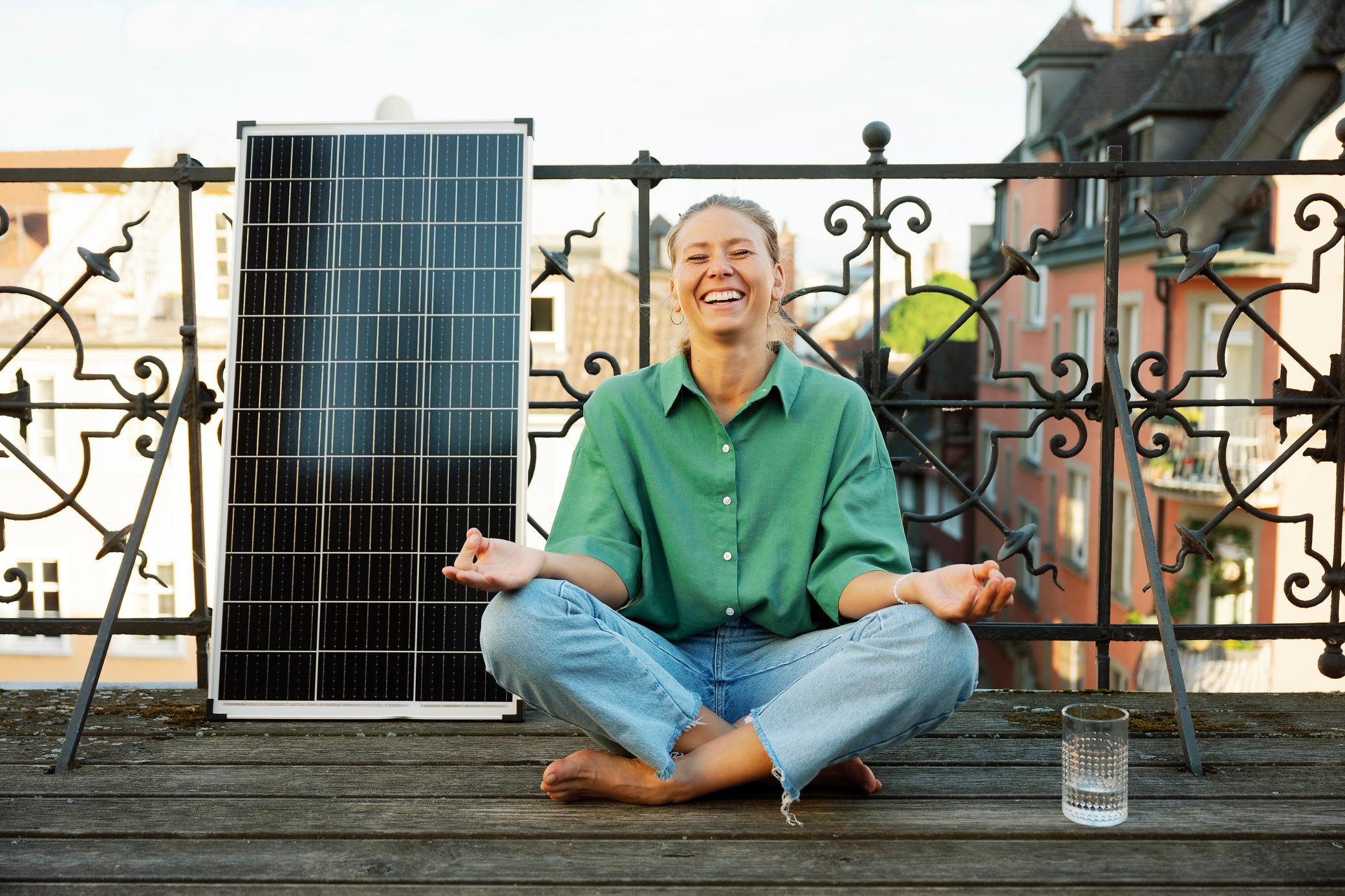 Mit einer Balkon Solaranlage senkst du entspannt Stromkosten Frau macht Yoga auf dem Balkon und neben ihr steht ein Solarmodul