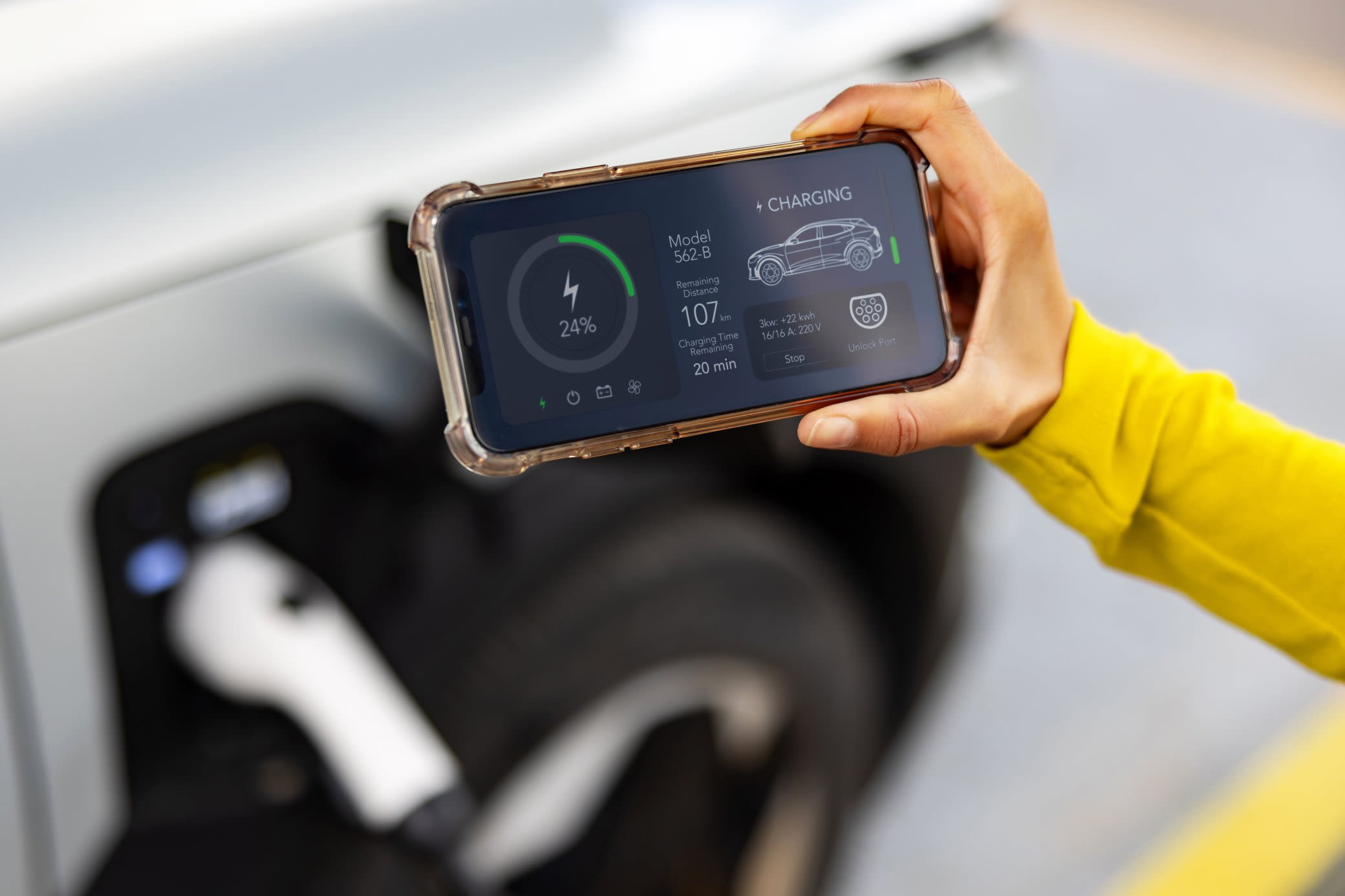 Lad dein Elektroauto smart und steure einfach alles per App Eine Person hält ein Smartphone mit App zur Überwachung des Ladevorgangs eines Elektroautos