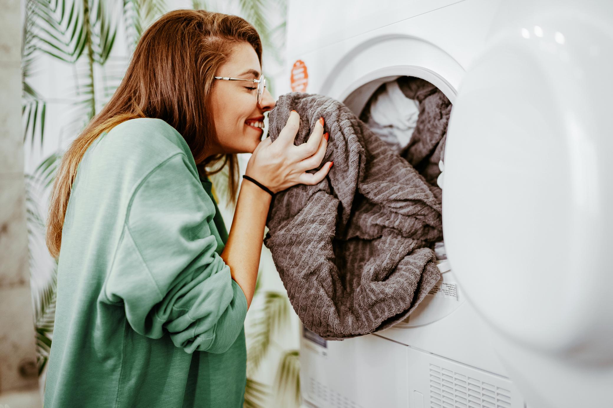 Eine junge Frau nimmt Wäsche aus der Waschmaschine