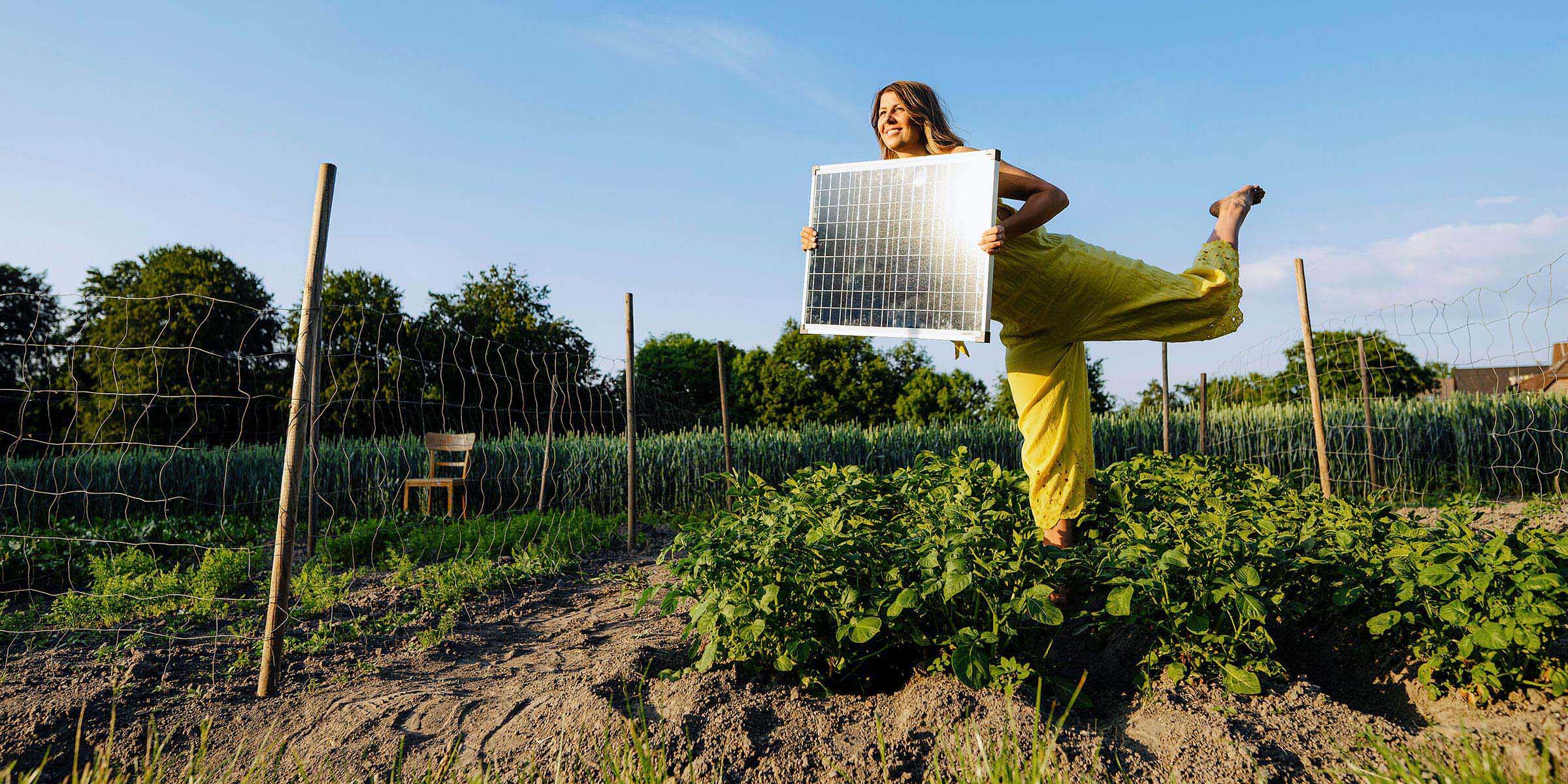 Frau mit Solarmodul in den Händen im Garten.