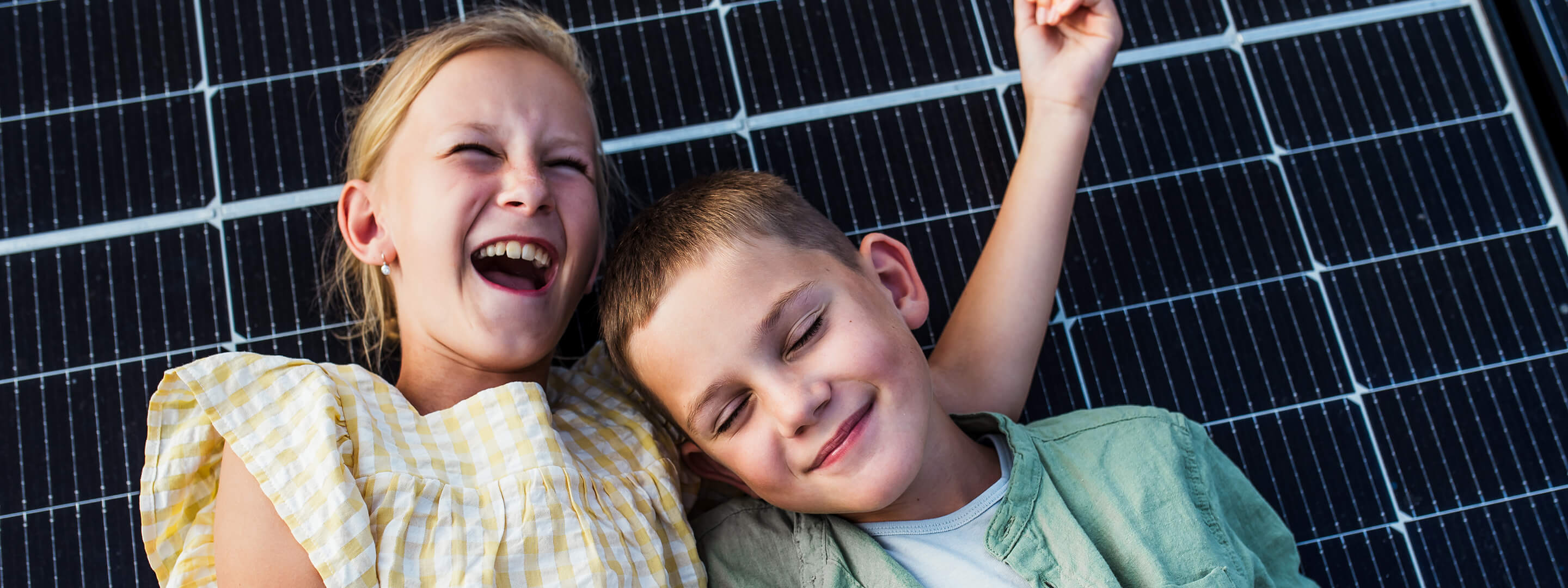 Mit Solarenergie in ein klimafreundliches Zuhause Familie lehnt fröhlich an einem Solarpanel und lacht