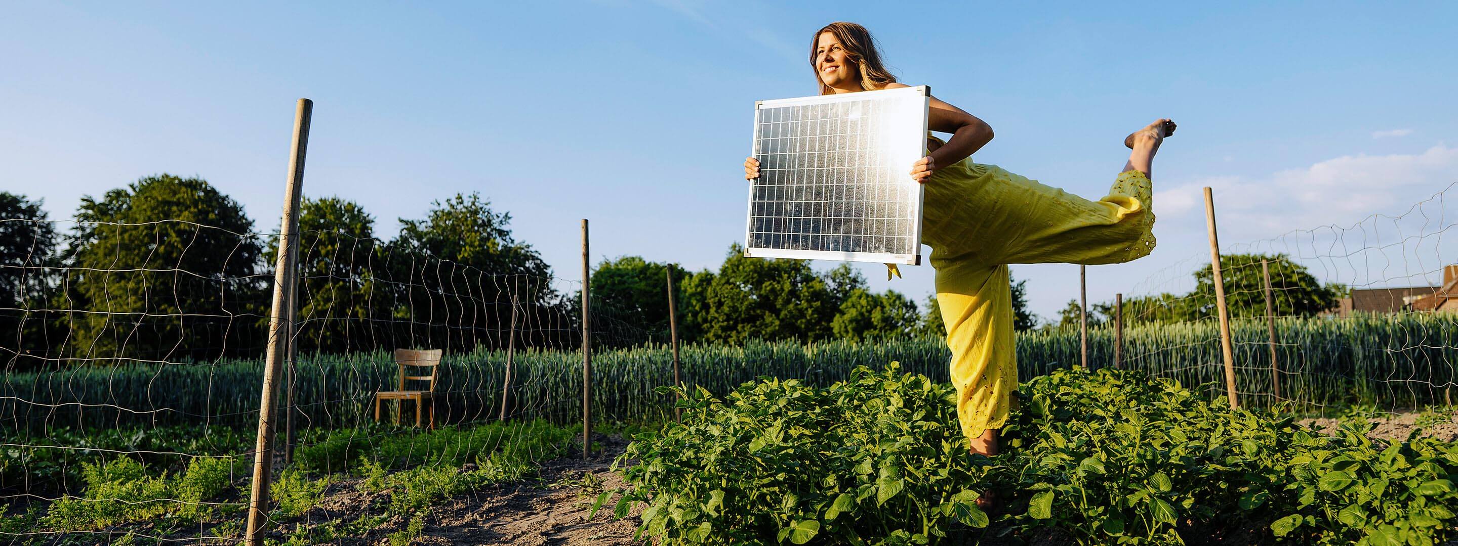 Frau mit Solarmodul in den Händen im Garten