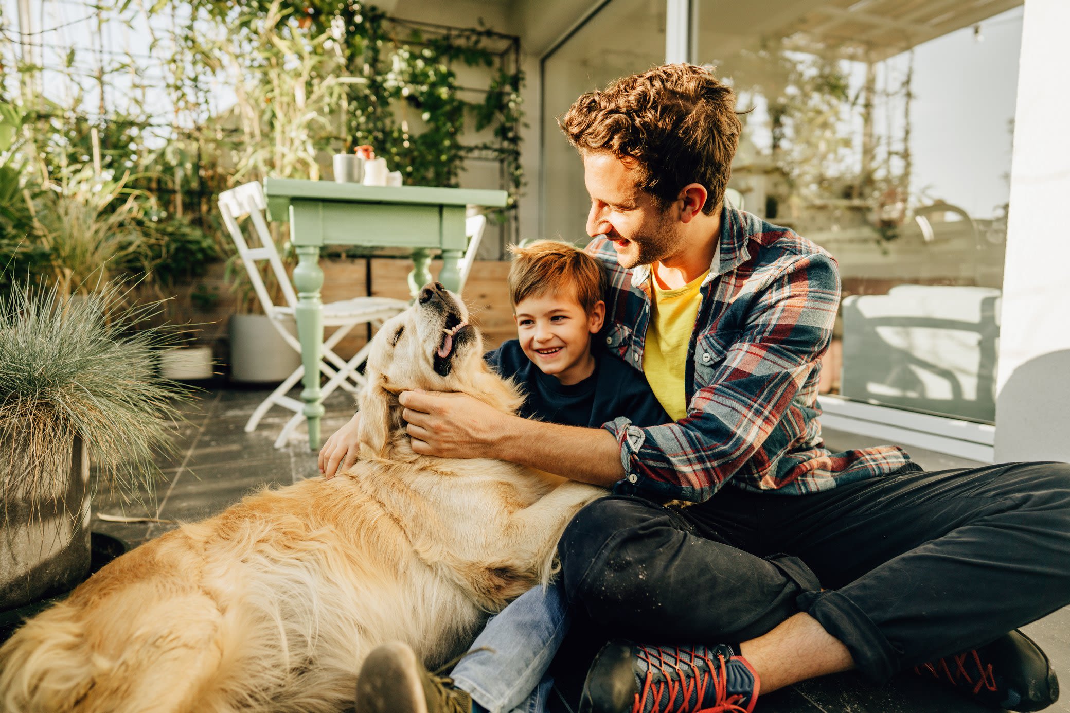 Das richtige PV-Komplettpaket? Es kommt auf dein Leben an! Vater mit Sohn sitzen lachend mit Hund auf der Terasse