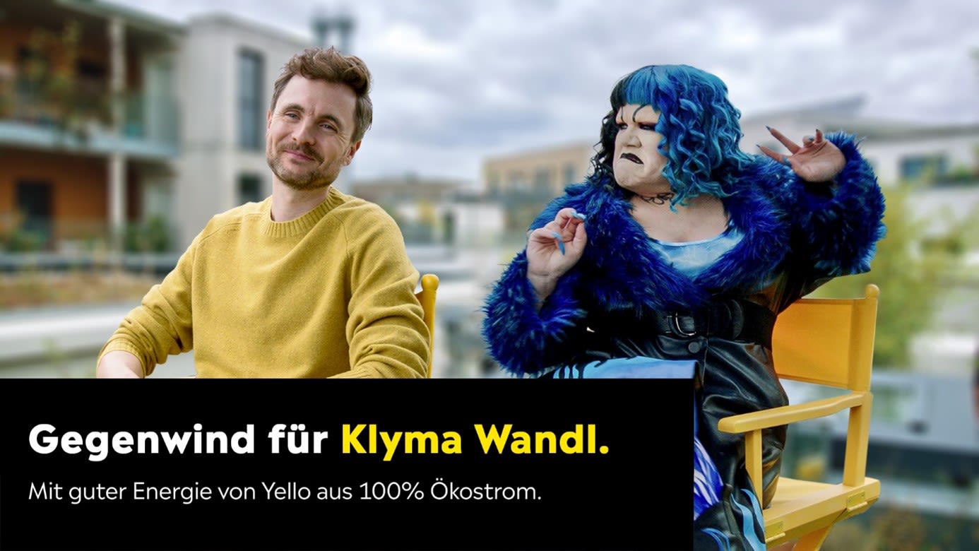 Klyma Wandl bekommt Gegenwind von Phil Laude Mann im gelben Pullover und Frau mit blauen Haaren und blauem Mantel sitzen nebeneinander auf Stühlen. Er schmunzelt, während sie grimmig aussieht.