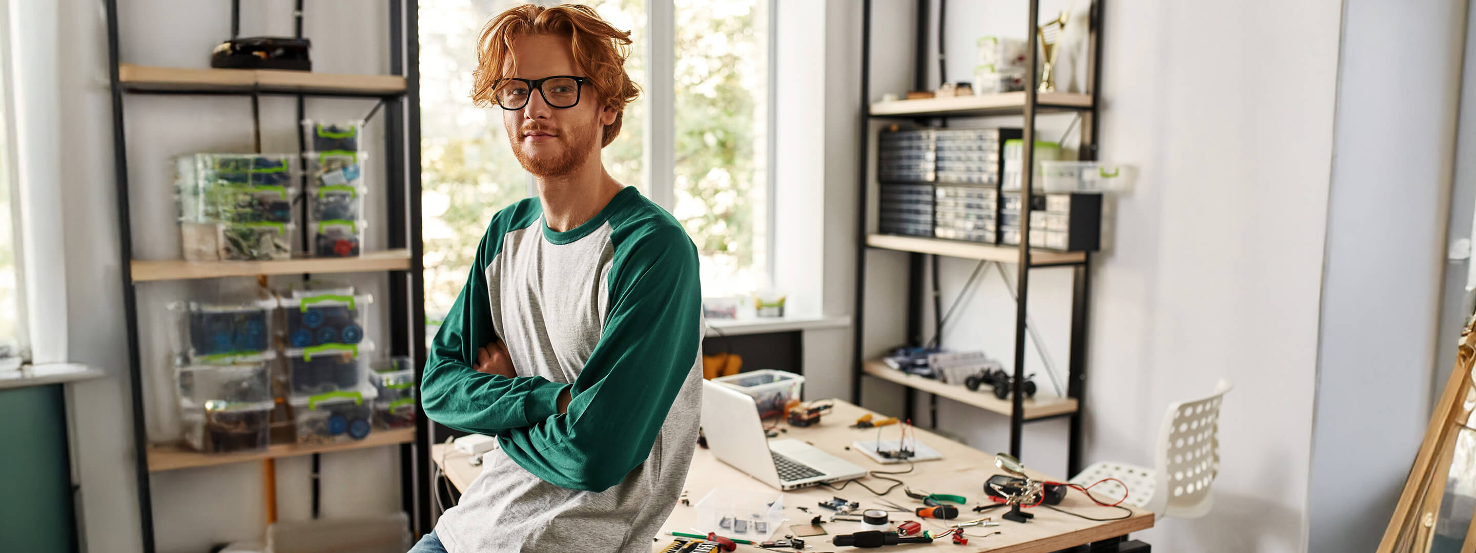Durchblicken bei den elektrischen Einheiten? Geht einfach mit Yello. Mann sitzt auf dem Tisch im Home-Office - im Hintergrund sind elektrische Bauteile zu sehen