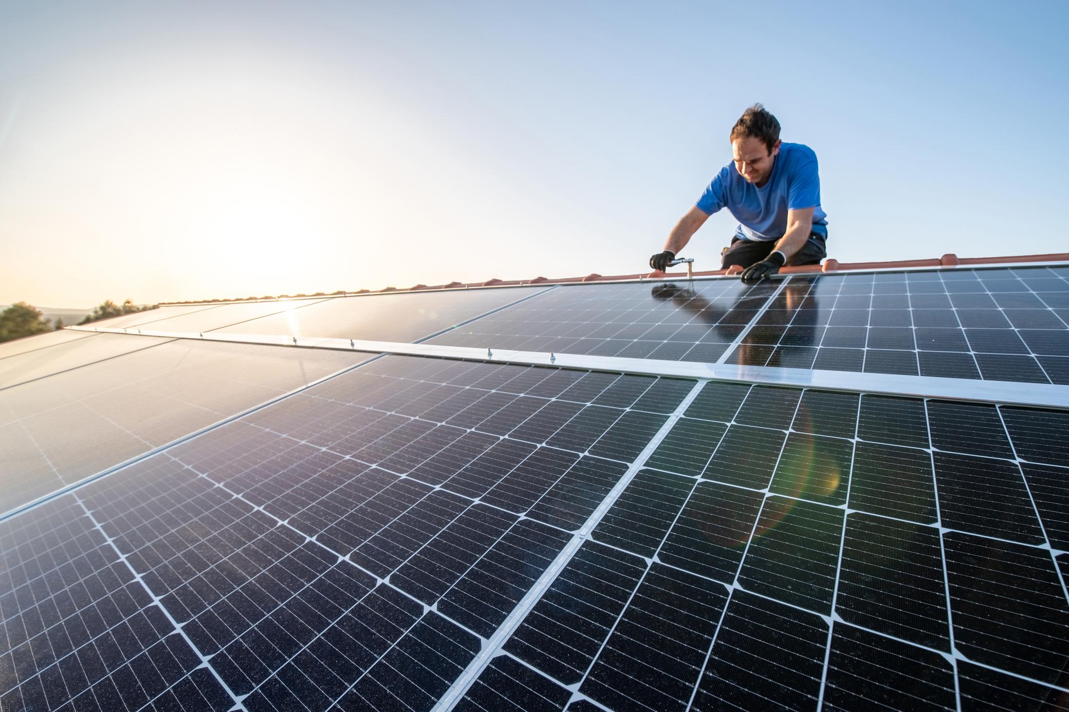 Mann installiert eine Photovoltaik-Anlage auf dem Dach