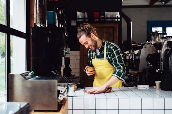 Grüner Strom für dein Gewerbe kommt von Yello Mann im Cafe vor Barista Maschinen bereitet Kaffee für Kunden und Gäste vor