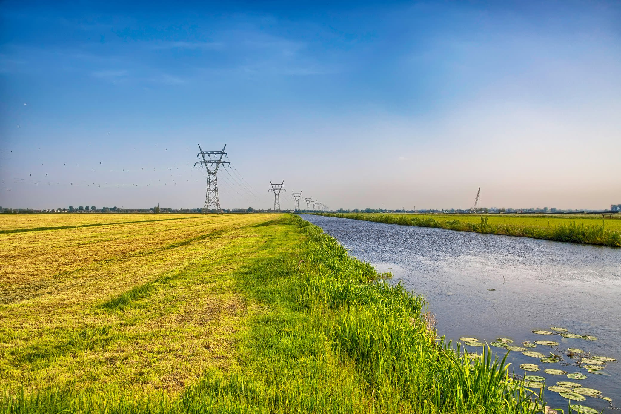 Strom Freileitungen verlaufen über der Erde und transportieren Strom mit höheren Spannungen Hochspannungsleitungen und Strommasten auf einem Feld an einem Kanal