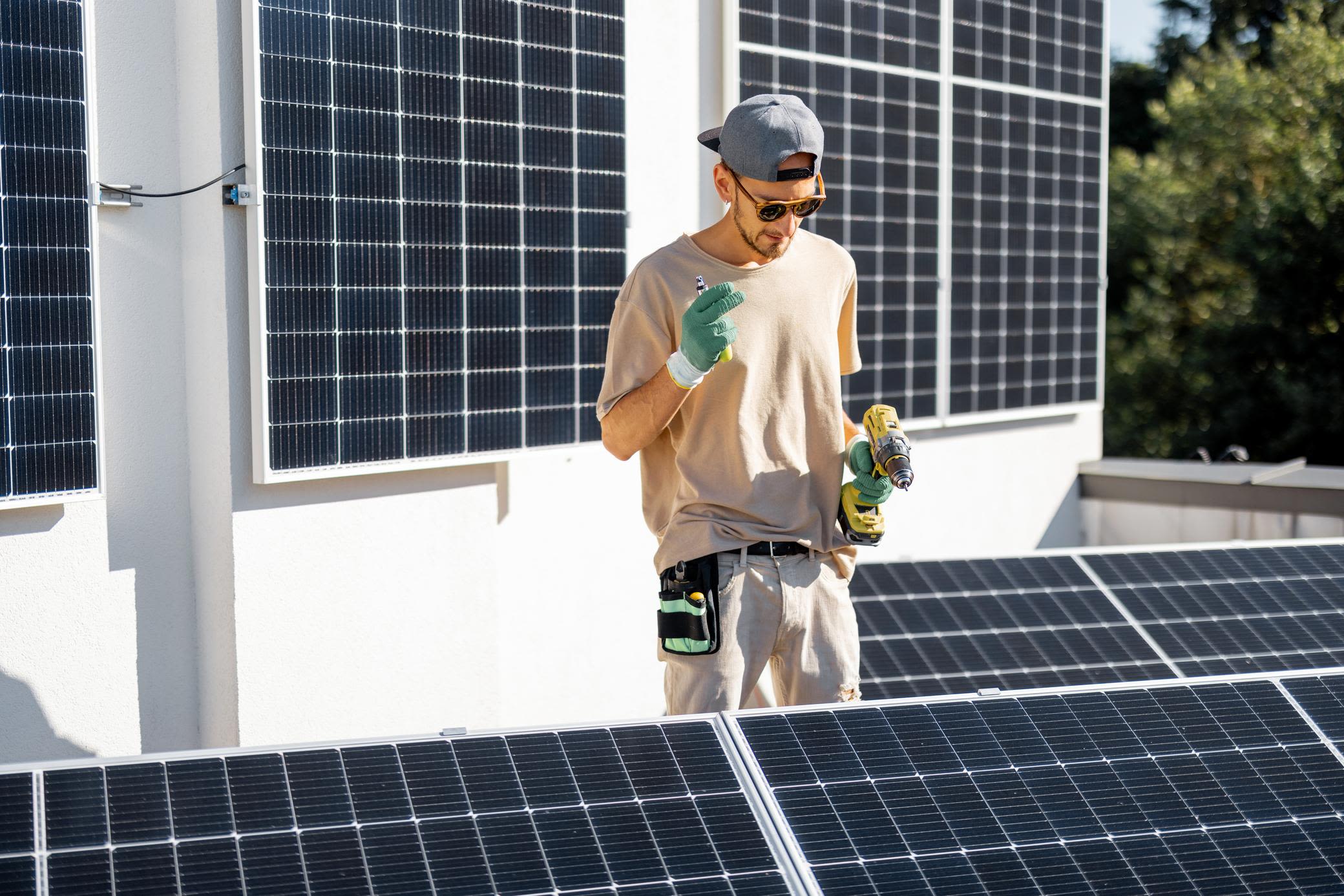 Solarmodule lassen sich auf fast jedem Dach einfach installieren Mann installiert Solarmodule auf einem Flachdach